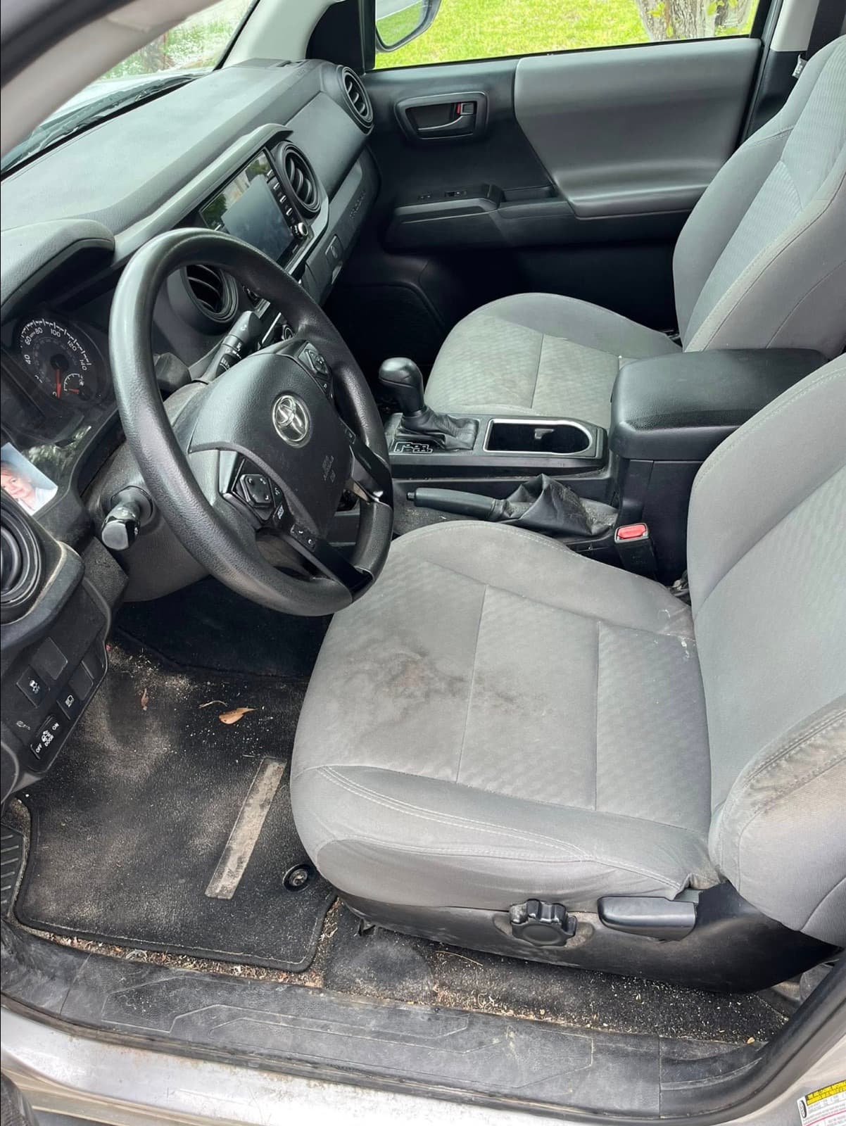 Toyota Tacoma driver-side interior before detailing — dusty dash and muddy fabric seats